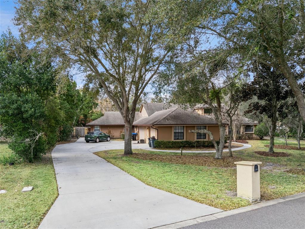 A single-story house with a concrete driveway, a green car, and mature trees — 5314 SHADYWOOD LANE, ORLANDO, FL