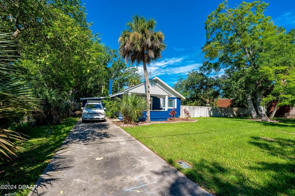 A blue house with a white roof and a driveway sits on a grassy lot — 112 CENTER STREET, DAYTONA BEACH, FL