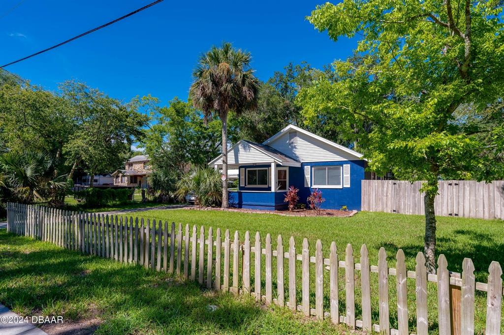 A blue house with a white porch and picket fence sits on a grassy lot — 112 CENTER STREET, DAYTONA BEACH, FL