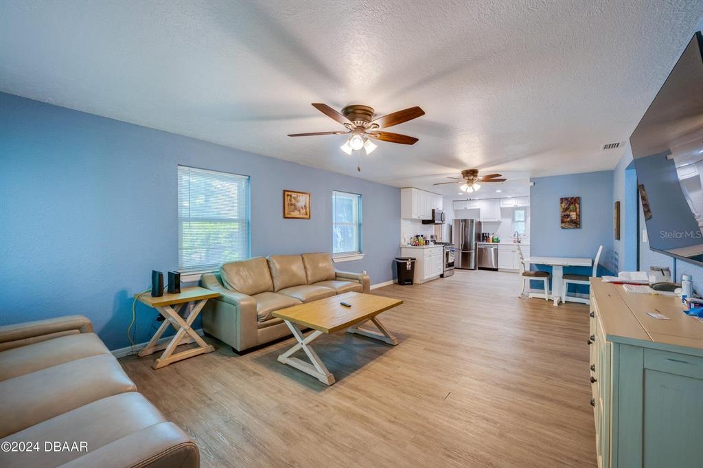 A living room with light blue walls, wood-look flooring, and an open-concept kitchen — 112 CENTER STREET, DAYTONA BEACH, FL