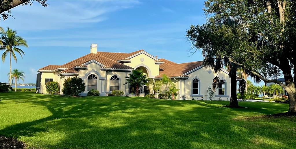 A large, light-colored single-story house with a tiled roof sits on a grassy lawn — 3121 RIVERSHORE LANE, PORT CHARLOTTE, FL