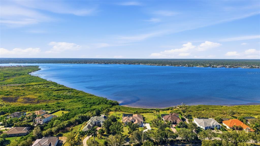 An aerial view shows several houses situated along the edge of a large lake — 3121 RIVERSHORE LANE, PORT CHARLOTTE, FL