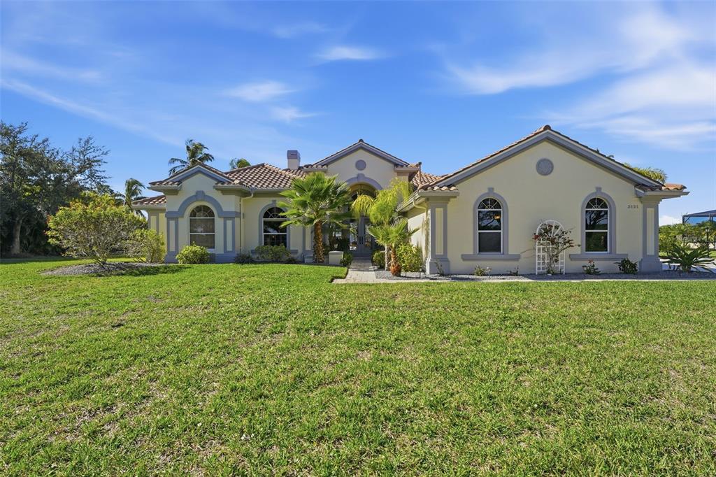 A single-story house with a tiled roof and light-colored stucco exterior sits on a lawn — 3121 RIVERSHORE LANE, PORT CHARLOTTE, FL