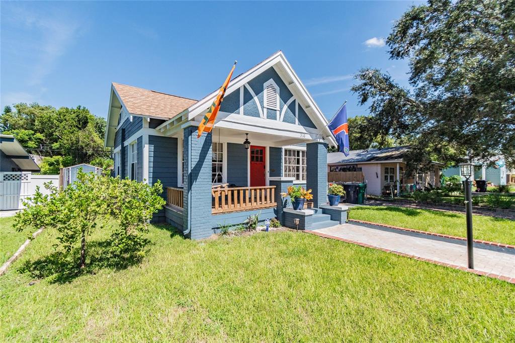 A covered front porch features a wooden swing, blue siding, and a bright red door — 310 E PARIS STREET, TAMPA, FL