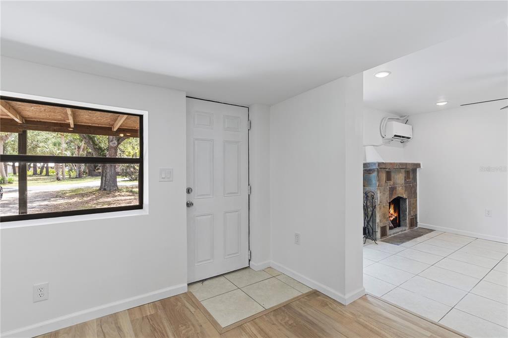 An entryway with a white door, tile flooring, and a view into a fireplace room — 23094 CENTRAL AVENUE, PORT CHARLOTTE, FL