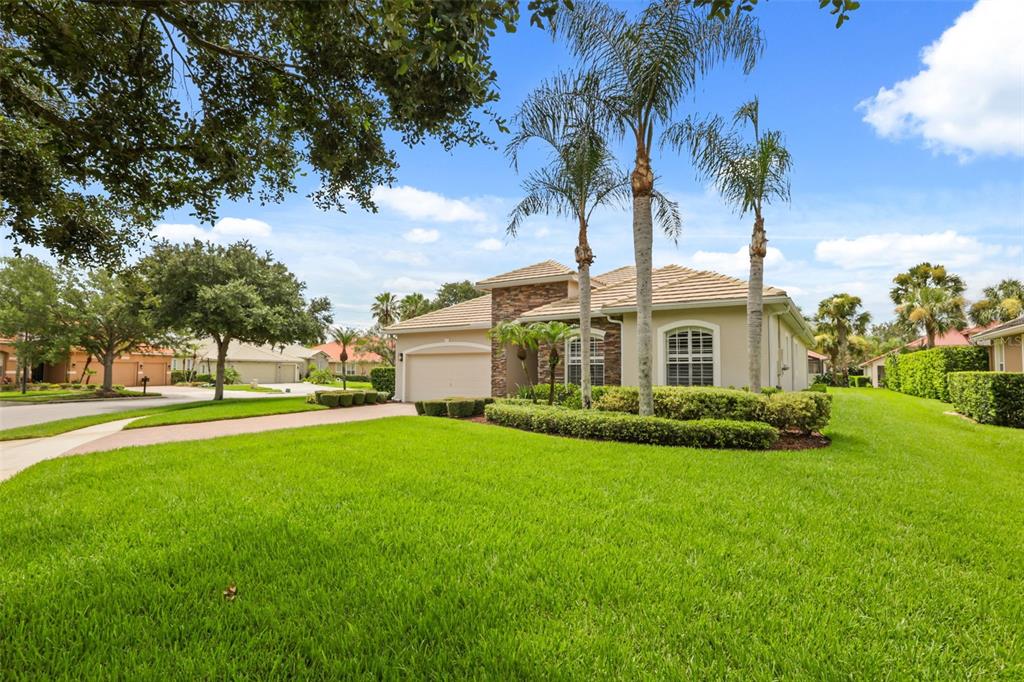 A single-story house with a tan exterior, stone accents, a tile roof, and palm trees — 843 WOOD BRIAR LOOP, SANFORD, FL