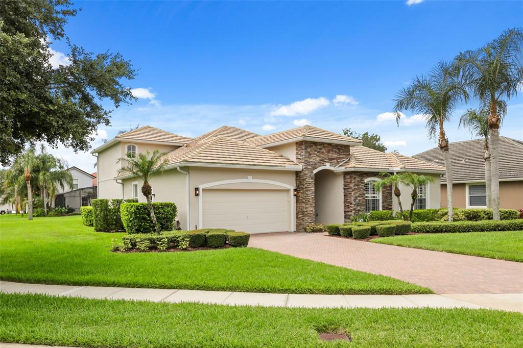 A single-story house with a stone facade, beige stucco, and a brick paver driveway — 843 WOOD BRIAR LOOP, SANFORD, FL