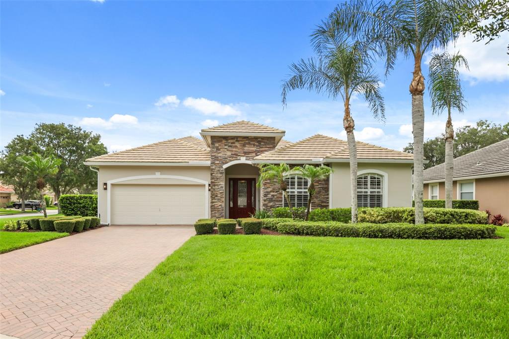 A single-story house with a stone facade, a two-car garage, and palm trees — 843 WOOD BRIAR LOOP, SANFORD, FL