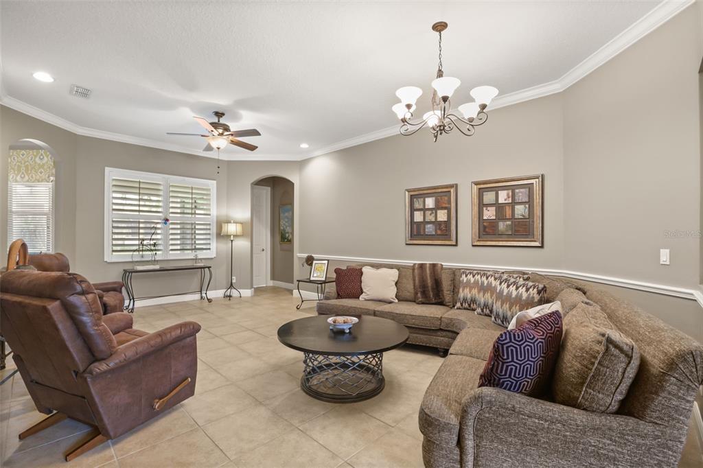 A living room features tile flooring, a sectional sofa, a recliner, and a chandelier — 843 WOOD BRIAR LOOP, SANFORD, FL