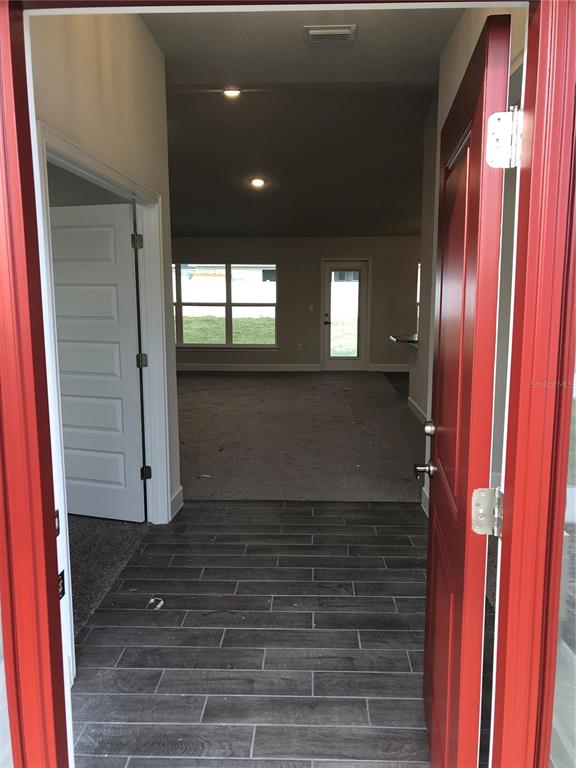 An entryway with gray wood-look tile flooring leads into a carpeted living area — 8744 SE 162ND STREET, SUMMERFIELD, FL