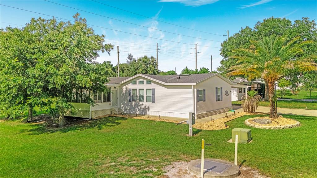A single-story manufactured home with light siding, a screened porch, and a palm tree — 58 FLORENCE BOULEVARD, DEBARY, FL