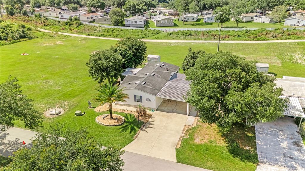 An aerial view shows a single-story house with a carport, palm tree, and large yard — 58 FLORENCE BOULEVARD, DEBARY, FL