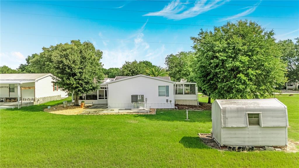A white house with a screened porch and a detached metal shed in a yard — 58 FLORENCE BOULEVARD, DEBARY, FL
