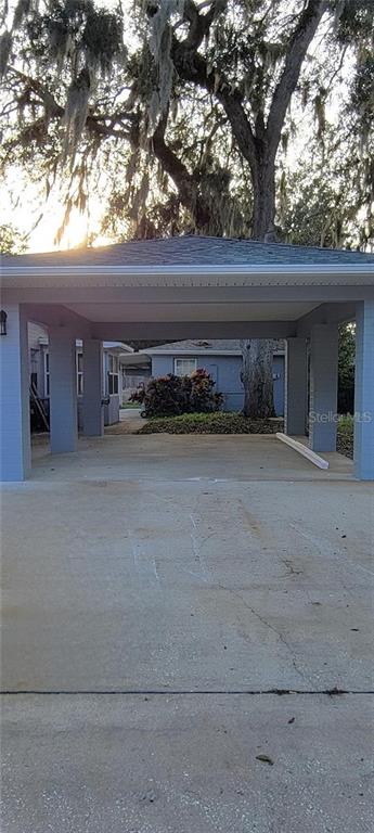 A concrete driveway leads to a covered carport attached to a single-story house — 340 TROPICAL LN, ORMOND BEACH, FL
