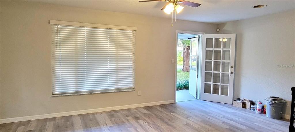 A room with light-colored wood-look flooring, a large window with blinds, and a glass-paneled door — 340 TROPICAL LN, ORMOND BEACH, FL