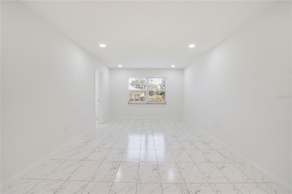 A bright, empty room features white walls, recessed lighting, and white marble-patterned tile flooring — 4013 LAKE BAYSHORE DR UNIT 107, BRADENTON, FL