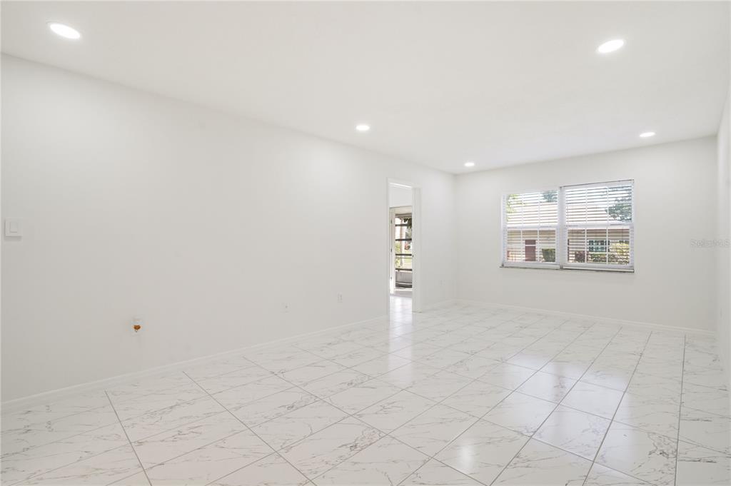A bright, empty room features white walls, recessed lighting, and white marble-patterned tile flooring — 4013 LAKE BAYSHORE DR UNIT 107, BRADENTON, FL