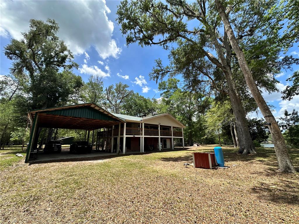 A two-story house with a large attached carport sits on a wooded lot — 3019 NE 709TH AVENUE, OLD TOWN, FL