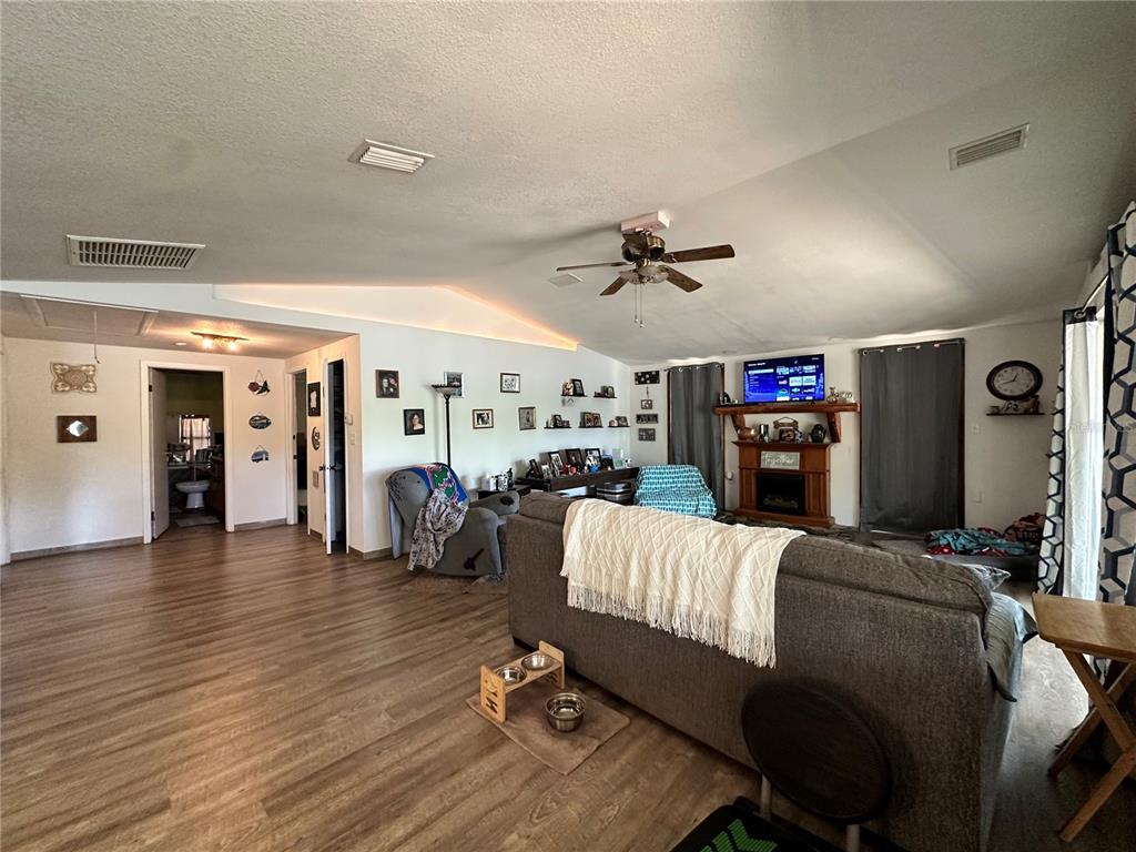 A living room features wood-look flooring, a vaulted ceiling, a fireplace, and a gray sofa — 3019 NE 709TH AVENUE, OLD TOWN, FL