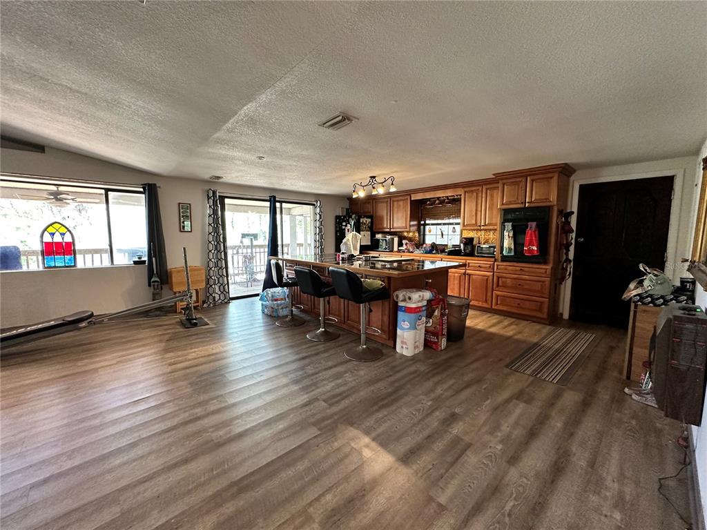 A kitchen with wood cabinets and a center island opens into a living area — 3019 NE 709TH AVENUE, OLD TOWN, FL