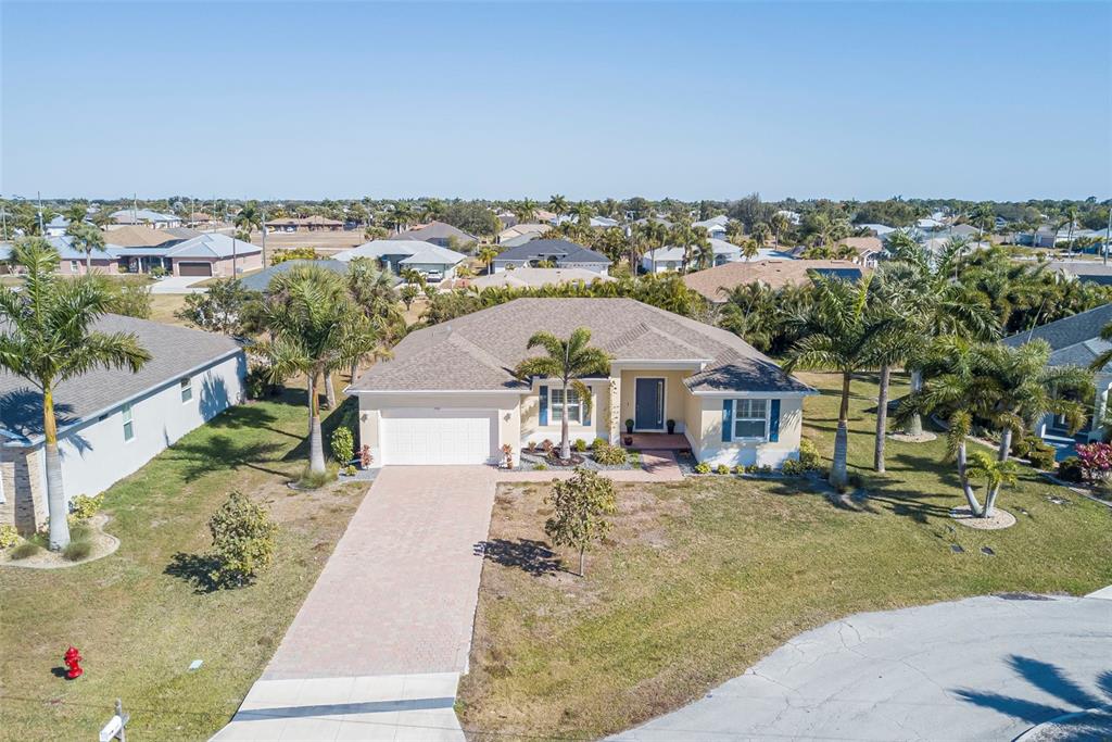 An aerial view shows a single-story house with a paved driveway and palm trees — 7416 S MOSS ROSE, PUNTA GORDA, FL