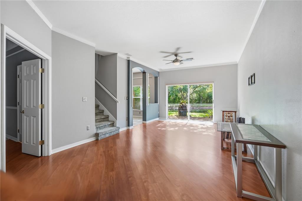 A living room with hardwood floors, a staircase, and a sliding glass door to outside — 11019 BLAINE TOP PLACE, TAMPA, FL