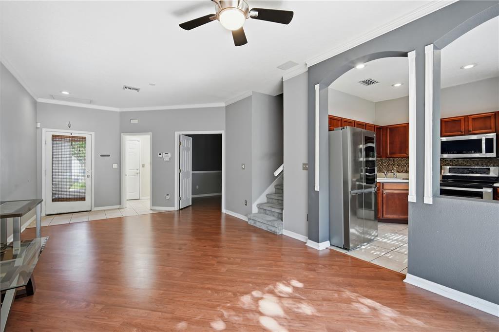 A living room with wood flooring leads to a kitchen with stainless steel appliances — 11019 BLAINE TOP PLACE, TAMPA, FL