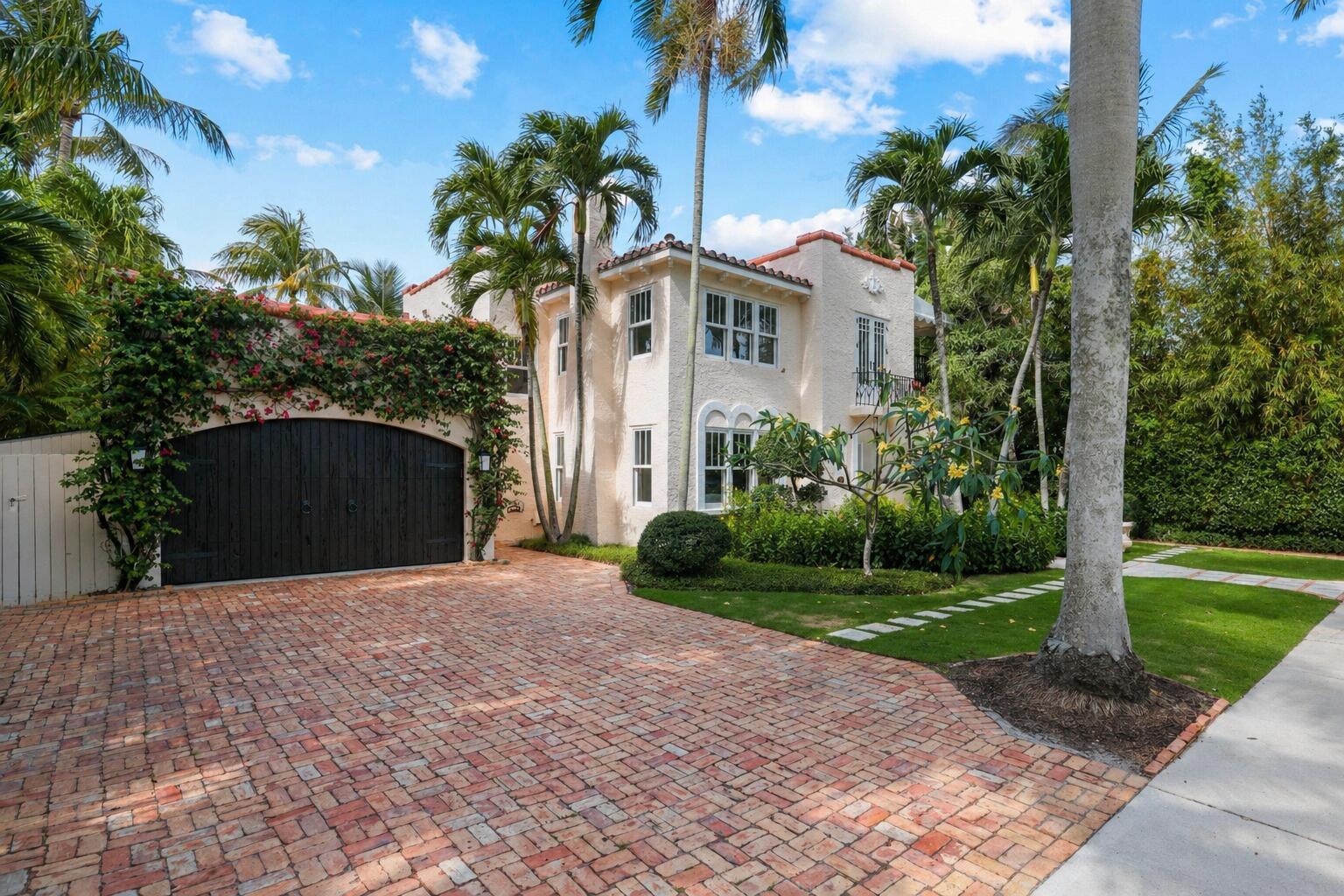 A two-story stucco house with a brick driveway, arched garage door, and lush tropical landscaping — 429 30th Street, West Palm Beach FL 33407, WEST PALM BEACH, FL