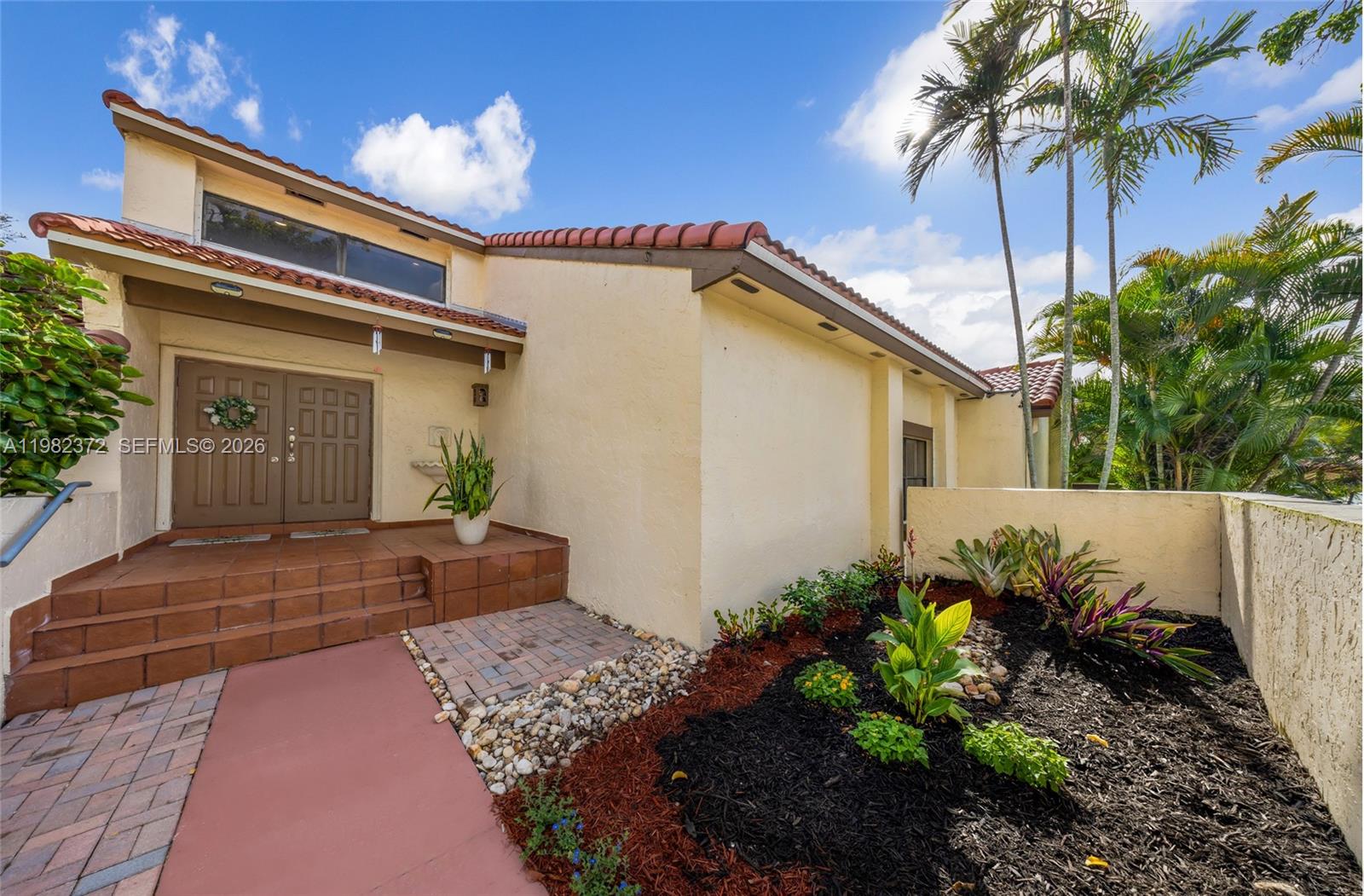 The exterior of a house features a tiled entryway, double doors, and a landscaped garden — 6637 NW 181st Ln # 6637, Hialeah FL 33015, HIALEAH, FL