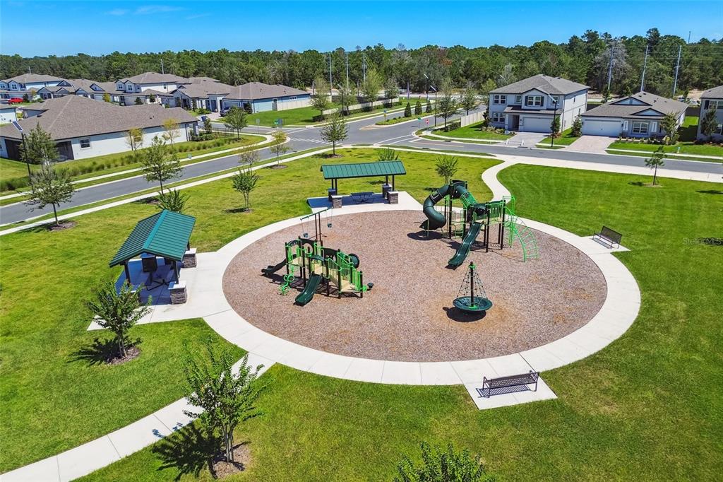 An aerial view of a neighborhood playground featuring green equipment, two pavilions, and paved paths — 1855 CLARY SAGE DRIVE, SPRING HILL, FL