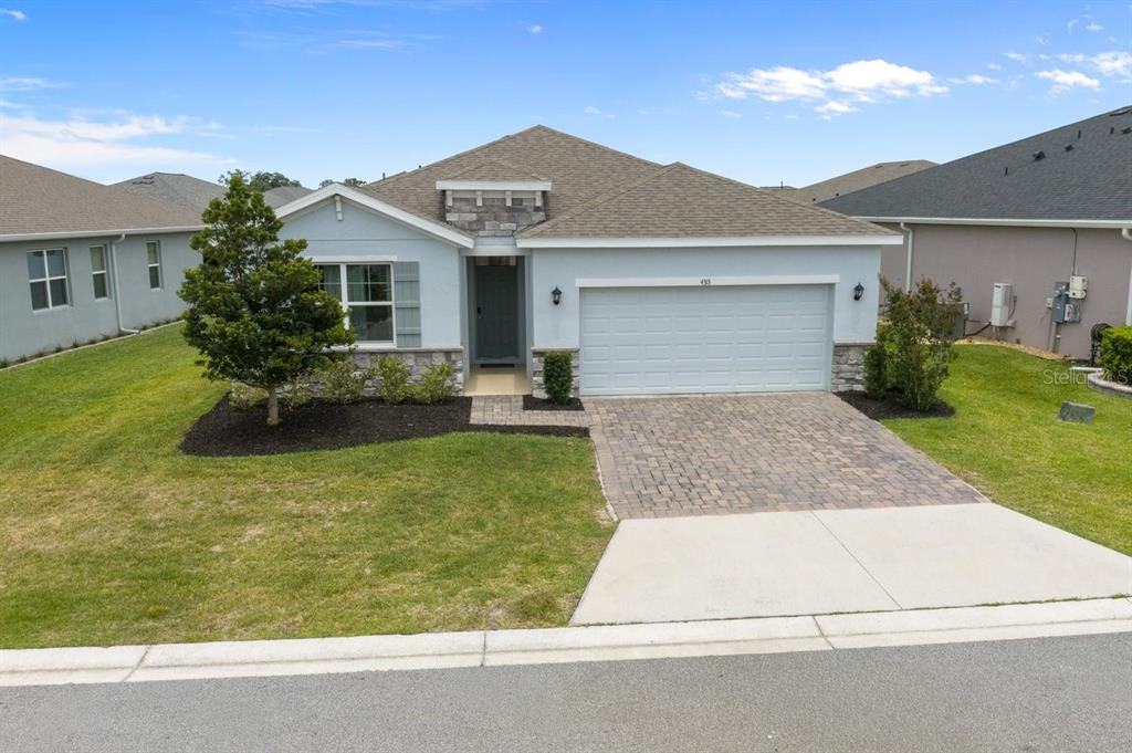 A single-story house with a light blue exterior, stone accents, and a paved driveway — 4313 NW 55TH COURT, OCALA, FL