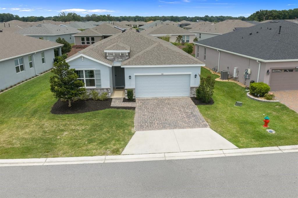 An aerial view of a single-story suburban house with a paved driveway and stone accents — 4313 NW 55TH COURT, OCALA, FL