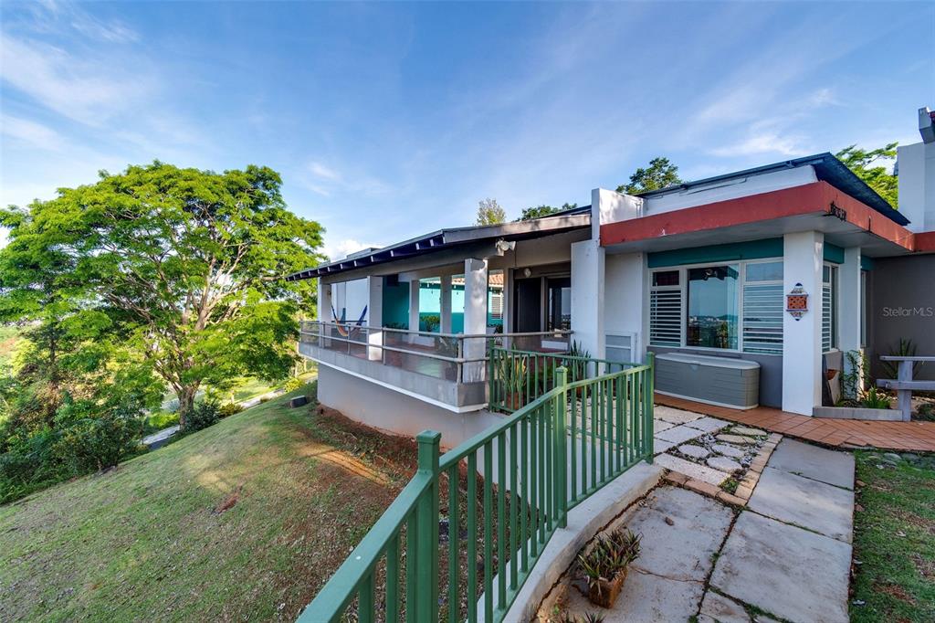 A house exterior features a balcony, green railings, and a paved walkway on a hillside — Bo Cerro Gordo, Carr 840 SECTOR VILLAS DEL OLIMPO, BAYAMON, PR