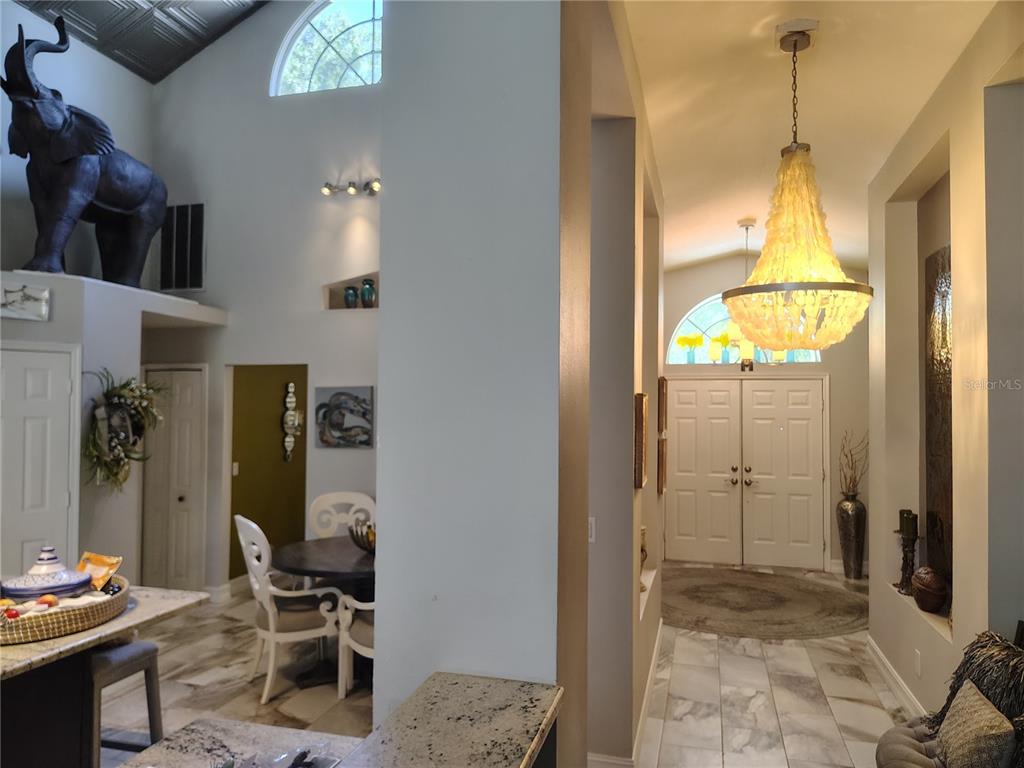 A view from a kitchen looking toward a foyer with a large chandelier and elephant statue — 15211 ARBOR HOLLOW DRIVE, ODESSA, FL
