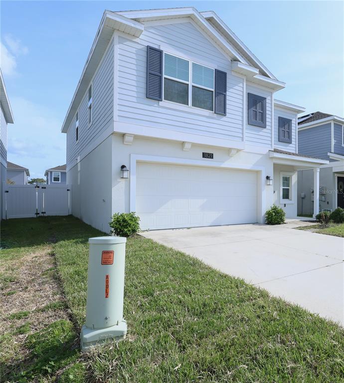 A two-story house with light blue siding, a two-car garage, and a utility box outside — 1821 HEART LAKE DRIVE, GROVELAND, FL
