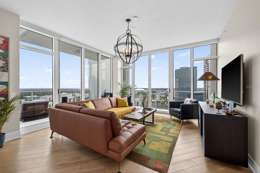 A modern living room features a leather sofa, floor-to-ceiling windows, and a city view — 175 1ST STREET S UNIT 3102, ST PETERSBURG, FL