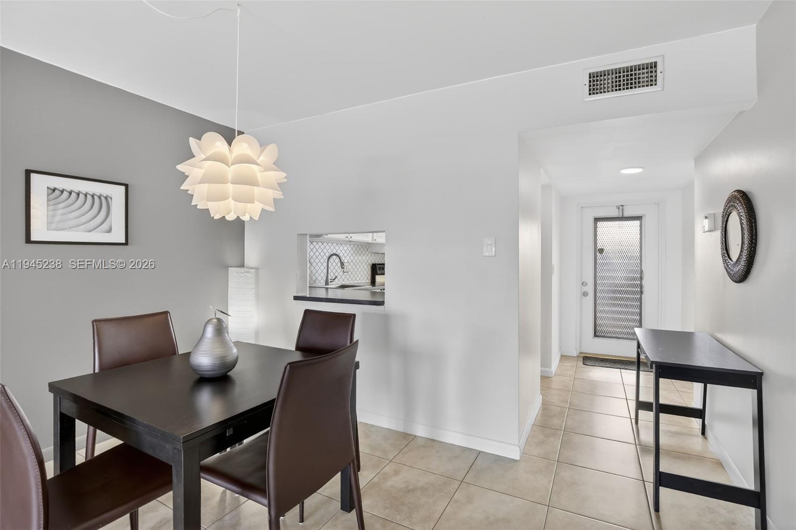 A dining area with a dark table and chairs sits adjacent to a kitchen pass-through window — 7897 Golf Circle Dr # 307, Margate FL 33063, MARGATE, FL