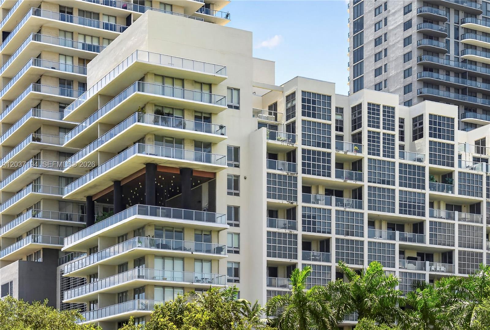 The exterior of a modern multi-story apartment building features stacked balconies and glass windows — 3451 NE 1st Ave, Miami FL 33137, MIAMI, FL