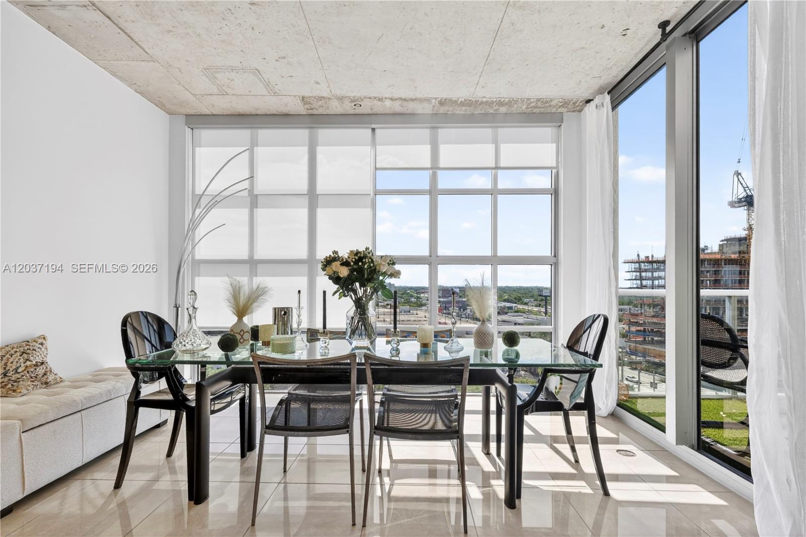 A dining area features a glass table, modern chairs, and floor-to-ceiling windows with city views — 3451 NE 1st Ave, Miami FL 33137, MIAMI, FL