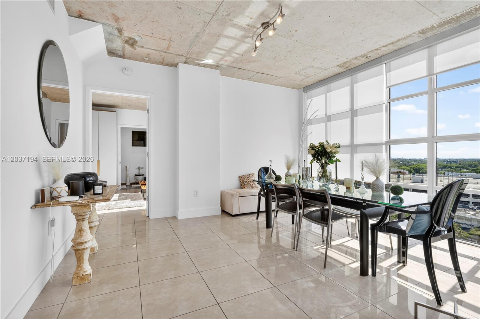 A dining area features a glass table, modern chairs, tile floors, and an exposed concrete ceiling — 3451 NE 1st Ave, Miami FL 33137, MIAMI, FL