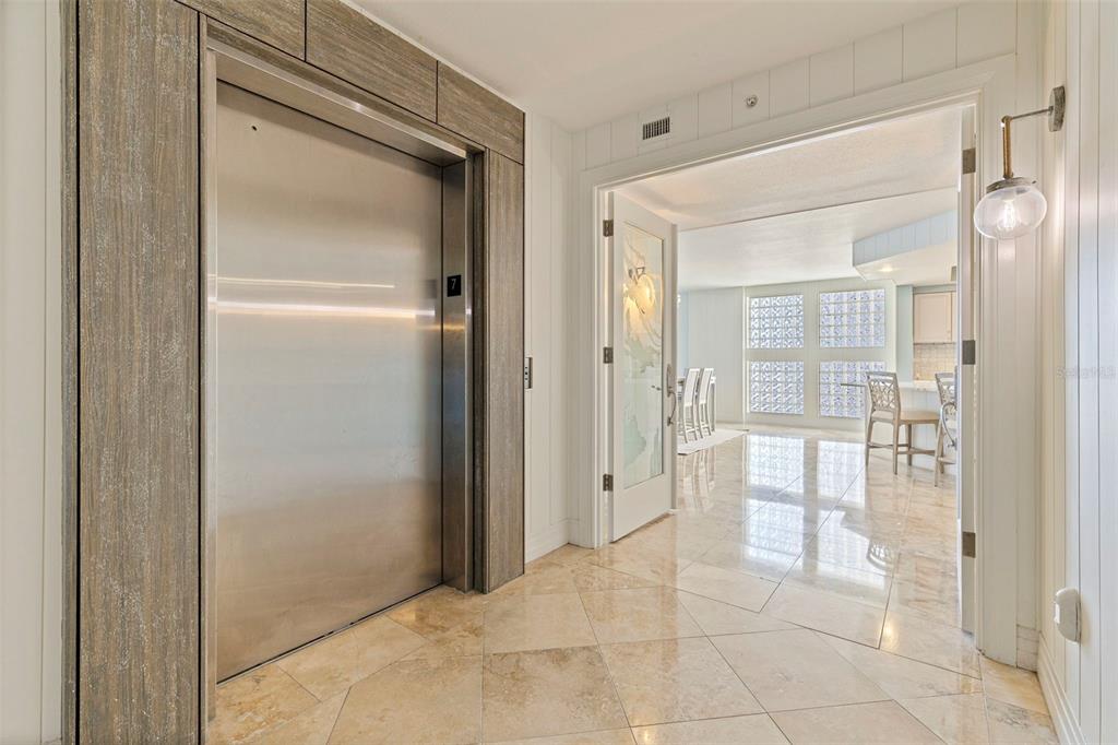 A private elevator opens into a tiled foyer leading to an interior room with glass blocks — 1350 GULF BOULEVARD UNIT 704, CLEARWATER BEACH, FL