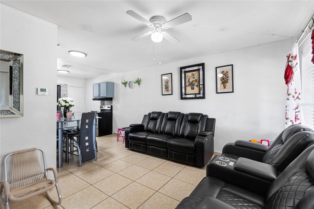 A living room with tile floors, black leather furniture, and a ceiling fan — 2313 E 111TH AVE, TAMPA, FL