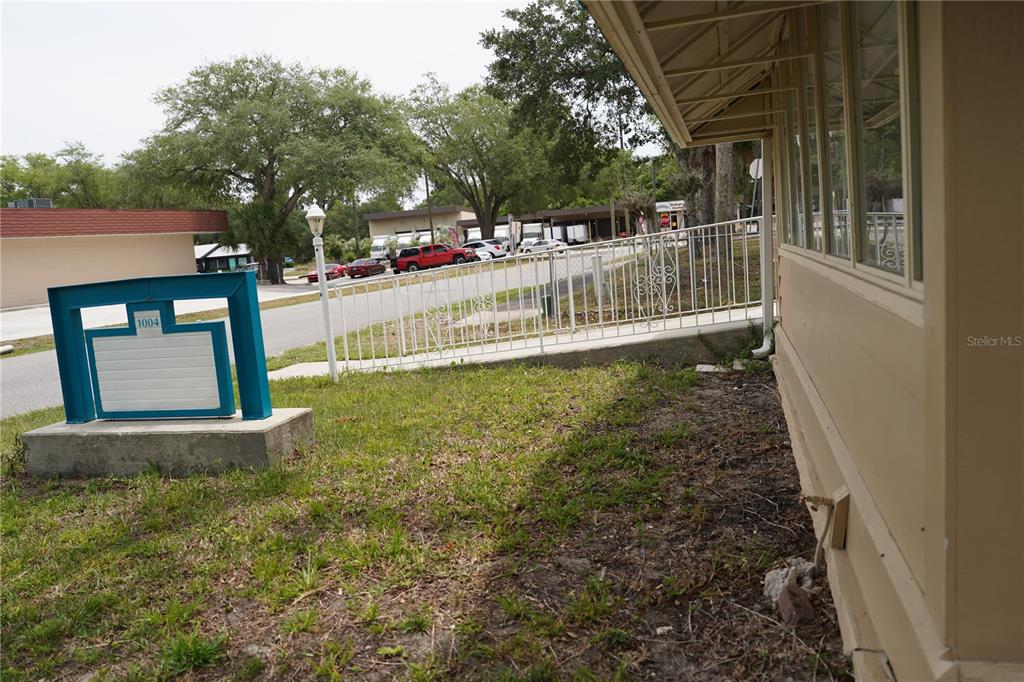 A view of a building exterior with a white metal fence and a blue sign — 1004 TALTON AVENUE, DELAND, FL