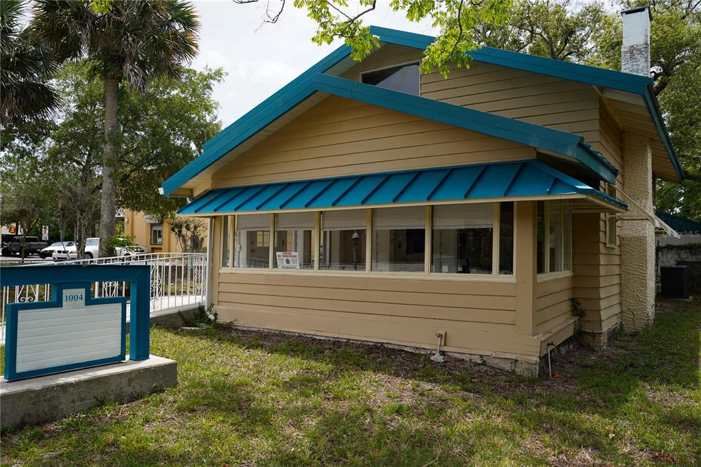 A tan, single-story house with a blue metal roof and a row of large windows — 1004 TALTON AVENUE, DELAND, FL