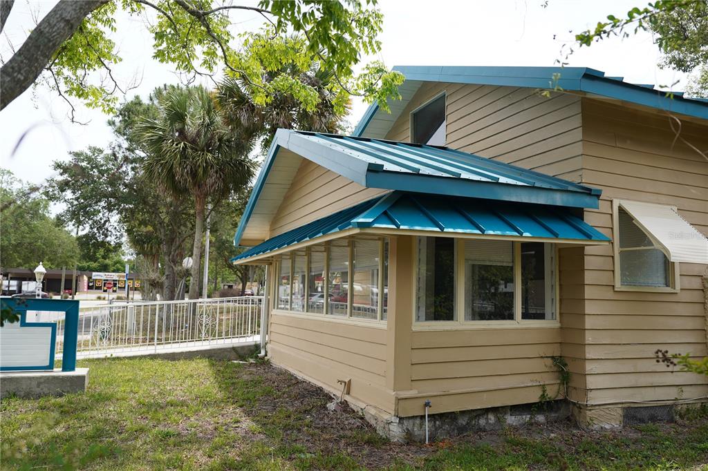 A tan house with a teal metal roof and a row of windows on the side — 1004 TALTON AVENUE, DELAND, FL
