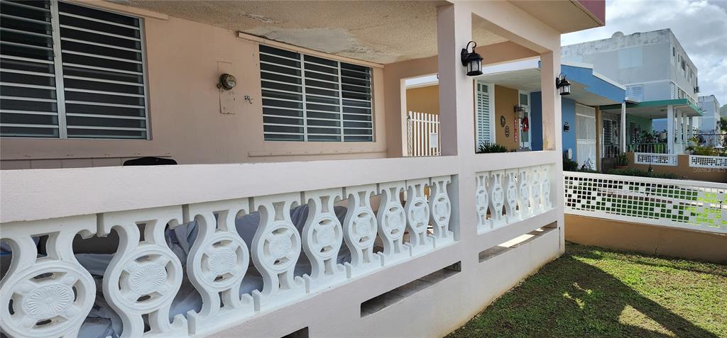 A covered porch features a white decorative concrete balustrade and horizontal window blinds — CALLE 8 BRISAS DE CEIBA UNIT 86, CEIBA, PR