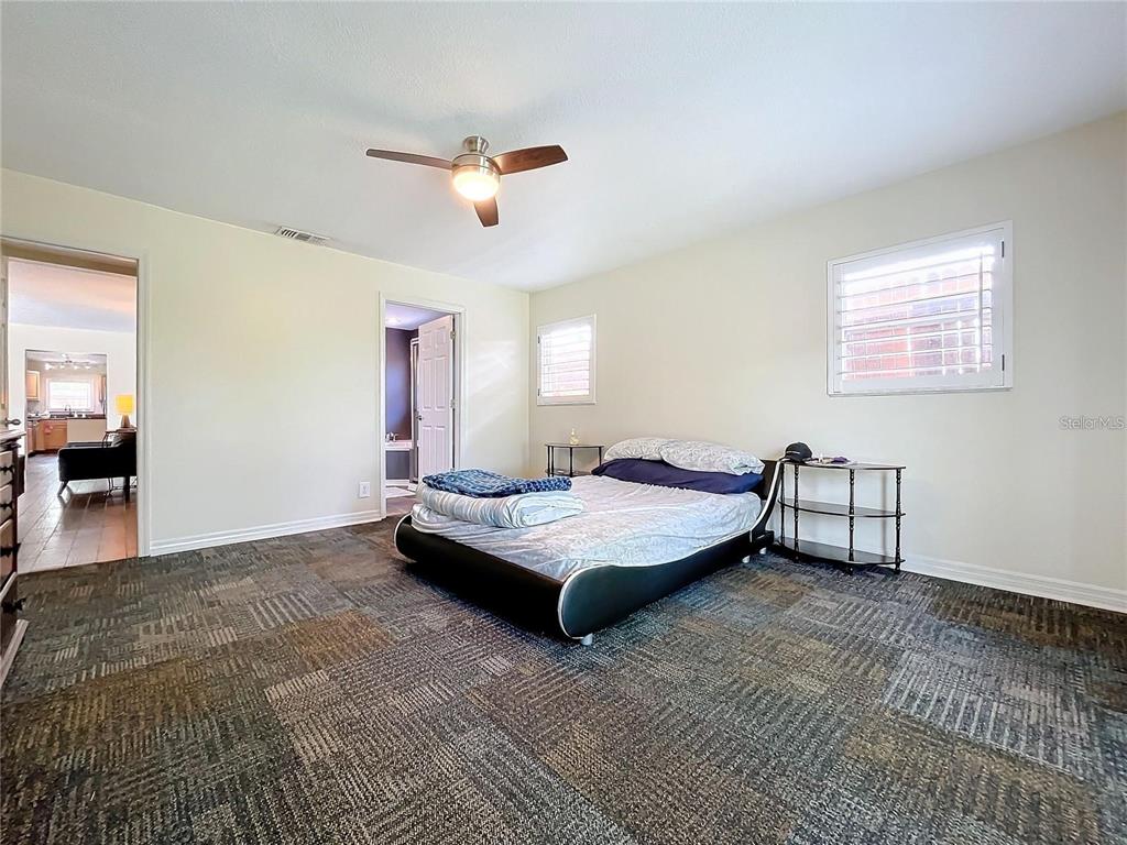 A bedroom with a platform bed, patterned carpet, and a ceiling fan — 33 S ORTMAN DRIVE, ORLANDO, FL