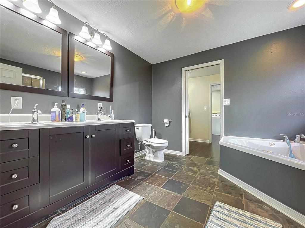 A bathroom features a dark wood double vanity, gray walls, and a corner soaking tub — 33 S ORTMAN DRIVE, ORLANDO, FL