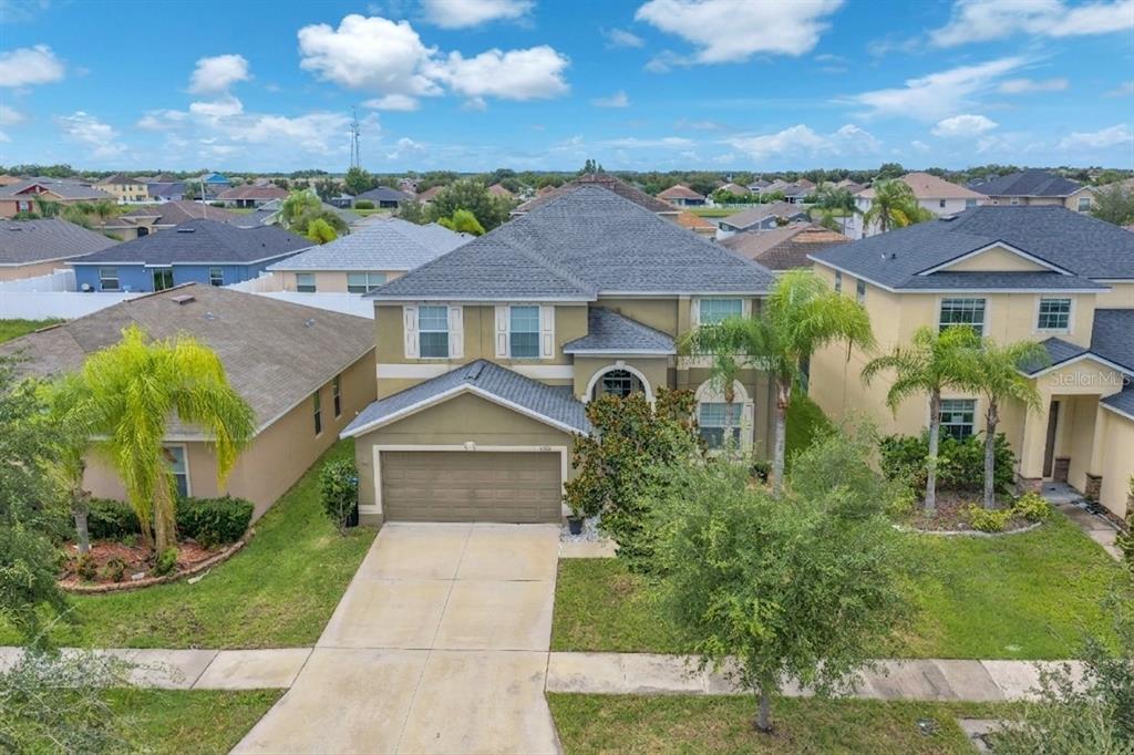 An aerial view of a two-story suburban house with a concrete driveway and palm trees — 10921 RAINBOW PYRITE DRIVE, WIMAUMA, FL