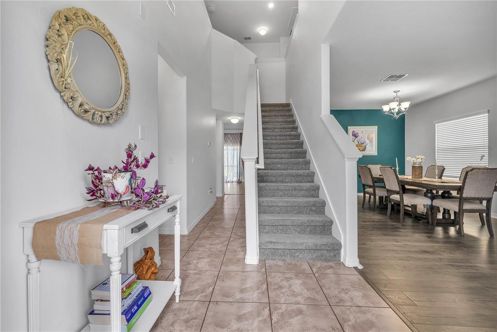 An entryway features a white console table, a staircase with gray carpet, and a dining room — 10921 RAINBOW PYRITE DRIVE, WIMAUMA, FL